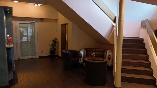 a living room with a staircase and a chair at Hotel Strand-Café in Roßbach