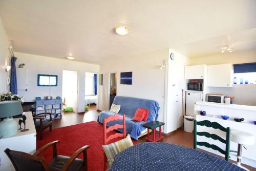 un salon avec un canapé bleu et une cuisine dans l'établissement HOSSEGOR RAYON VERT - En front de mer superbe vue océan, plages, Pyrénées, estacade et pinède, à Soorts-Hossegor