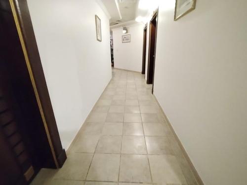 um longo corredor com paredes brancas e piso em azulejo em شقق الفرسان حي السلامة em Jidá