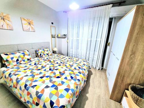 ein Schlafzimmer mit einem Bett mit einer bunten Bettdecke in der Unterkunft Nevila's apartment in Tirana