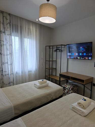1 dormitorio con 2 camas y TV en la pared en Lap Home Kavala, en Kavala