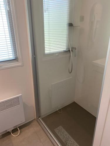 d'une douche avec une porte en verre et une fenêtre. dans l'établissement Location de vacances en campagne avec accès piscine, à Beaucaire