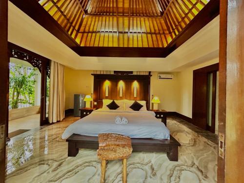 a bedroom with a large bed and a wooden ceiling at Mai Villa in Jimbaran