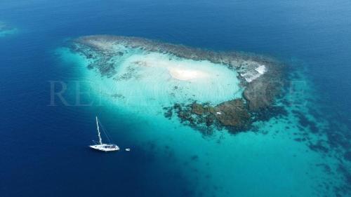 an island with a sail boat in the ocean at 73ft Family Sailing Yacht with Crew - all inclusive in Waisalatupo