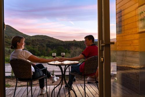 a man and woman sitting at a table with glasses of wine at O Refugio Nas Vinhas in Badim