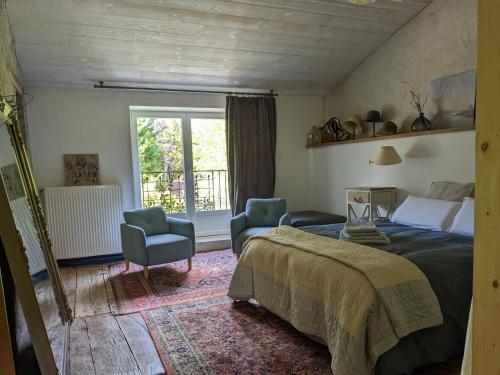 a bedroom with a bed and two chairs and a window at Domaine Dauget in Saint-Maurice-la-Clouère