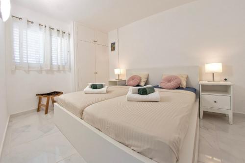 een witte slaapkamer met 2 bedden en roze kussens bij Colourful Bright Centred Apt. with Ocean View in Playa Fañabe