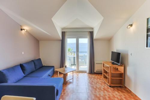 a living room with a blue couch and a tv at Villa Toni in Dugi Rat