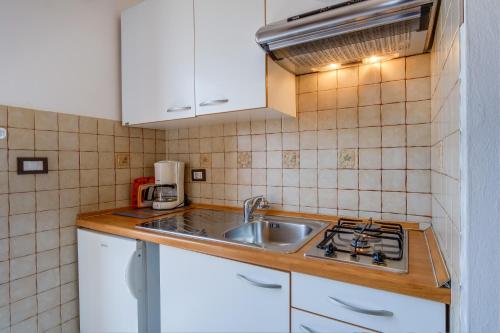 a small kitchen with a sink and a stove at Apartmani Ivo in Martinšćica