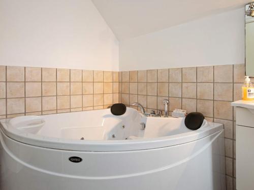 a white tub in a bathroom with a tiled wall at 6 person holiday home in V ggerl se in Marielyst
