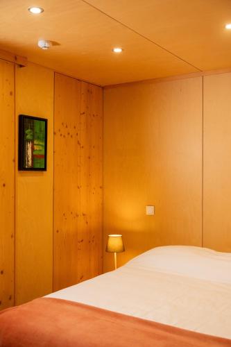 a bedroom with a white bed and wooden walls at O Refugio Nas Vinhas in Badim