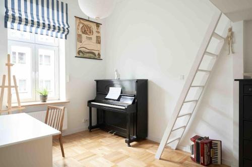 een piano in een woonkamer met een ladder bij Lovely central flat with soul by the river Wisła in Krakau