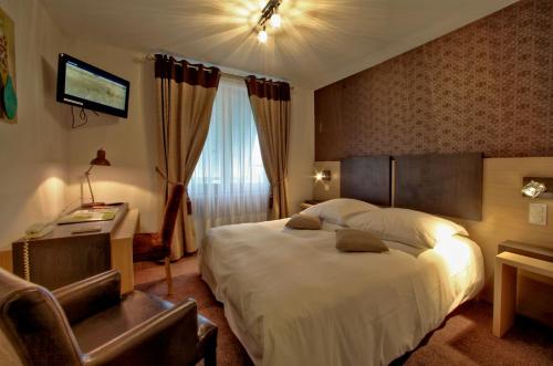 una habitación de hotel con una cama grande y una silla en LOGIS Auberge DE LA TRUFFE en Sorges