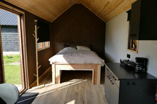 Cama en habitación pequeña con ventana en Tinyhouse Giethoorn en Giethoorn