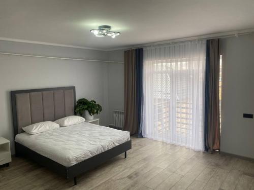 a bedroom with a bed and a large window at Bagysh Hotel in Kochkor