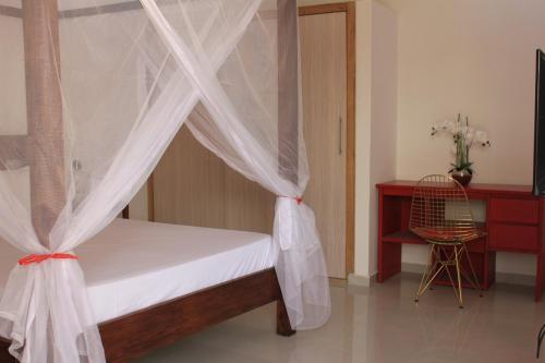 a bedroom with a bed with curtains and a desk at Amour Sénégal in Ngaparou