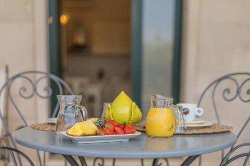 a table with a plate of fruit and a pitcher of orange juice at Villa Caramia in Locorotondo