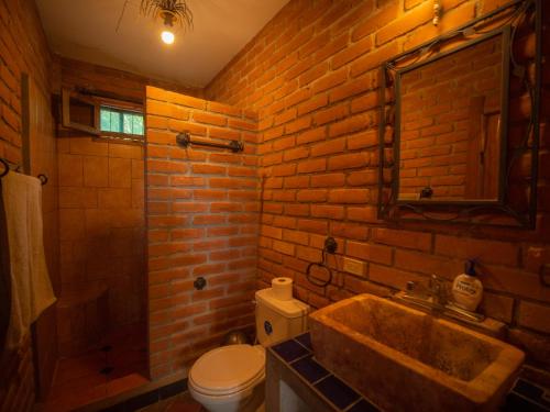 a brick bathroom with a sink and a toilet at 2 bedroom apartment in lush garden, 3 blocks from beach and center of San Juan in San Juan del Sur