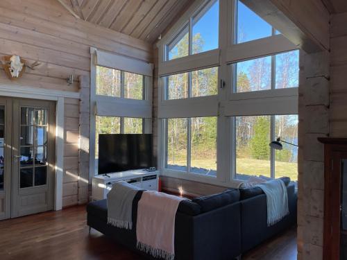 ein Wohnzimmer mit einem Sofa und einem Flachbild-TV in der Unterkunft Villa Mustalahti in Mikkeli