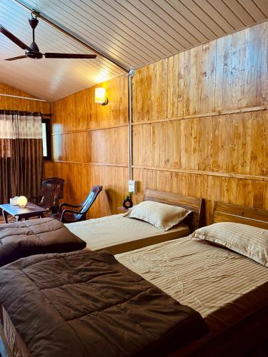 Duas camas num quarto com paredes de madeira em Stay In Woods em Bogmalo