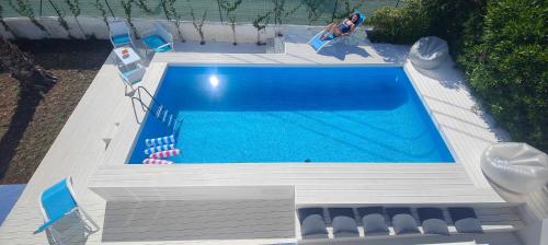 an overhead view of a swimming pool with chairs and a woman at Pool Seaside Relais - VILLE Ninfea, Marea, Rosa e Cassiopea in Fontane Bianche