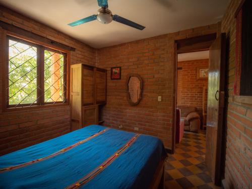 een slaapkamer met een blauw bed en een bakstenen muur bij 2 bedroom apartment in lush garden, 3 blocks from beach and center of San Juan in San Juan del Sur