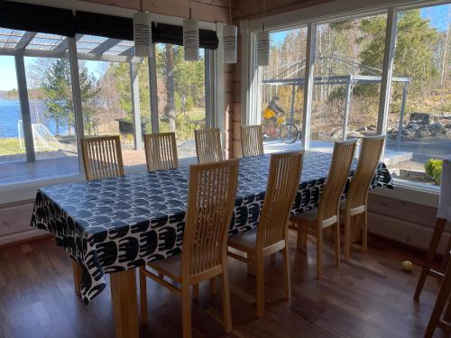 comedor con mesa, sillas y ventanas en Villa Mustalahti, en Mikkeli