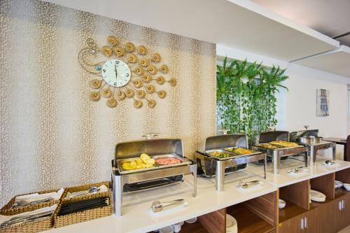 ein Buffet mit Tabletts voller Essen und einer Uhr in der Unterkunft Golden Light Da Nang Hotel in Đà Nẵng