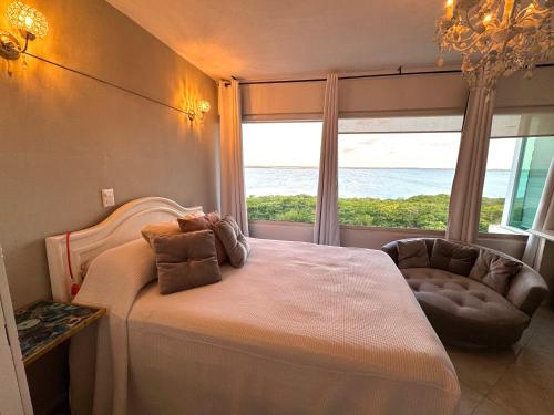 um quarto com uma cama com uma janela e uma cadeira em Beach Penthouse with Unique Rooftop Suite & Gorgeous Views em Cancún