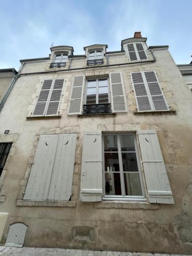 un edificio antiguo con persianas y ventanas blancas en Lémaliv, en Orléans
