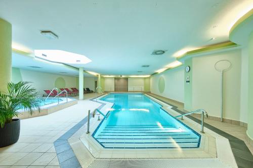 una gran piscina cubierta en una sala de hospital con un edificio de la aospital en Strandhotel Seehof, en Langlau
