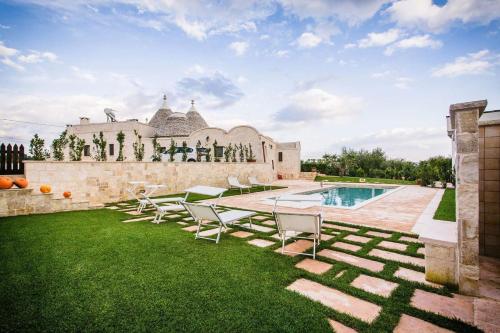 a backyard with chairs and a swimming pool at Trulli Magravì - Apparthotel in Alberobello
