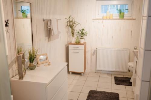 a white bathroom with a sink and a toilet at BUCHLINDENWEG - Zimmer & Ferienwohnung in Breitscheid