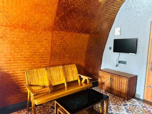 a room with a bench and a tv on a wall at Wild Brooke Hut in Vythiri