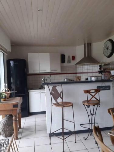 - une cuisine avec un comptoir et deux tabourets dans l'établissement Maison chaleureuse au calme, à Cast