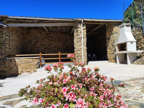 un bâtiment en pierre avec des fleurs roses devant lui dans l'établissement Casa Carlán, à Melide