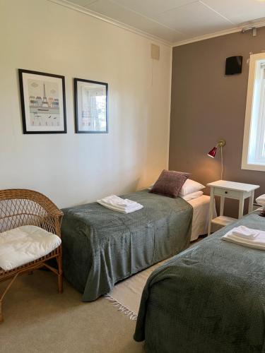 a bedroom with two beds and a chair and a window at Bosdalhuset in Lavik