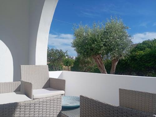 a patio with two chairs and a white wall at Apanema Paros in Naousa