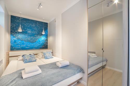グディニャにあるCITYSTAY Pilsudskiego Apartmentのベッドルーム1室(ベッド2台付)が備わります。壁には絵画が飾られています。