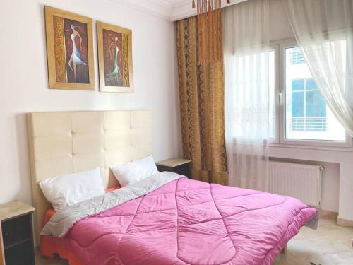 a bedroom with a pink bed and a window at Maison de peinture in Sidi Daoud