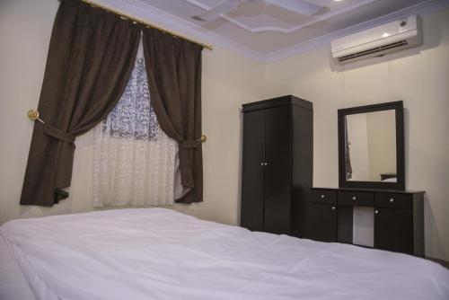 a bedroom with a bed and a dresser and a mirror at العييري للوحدات السكنية القصيم 1 in Quaniya