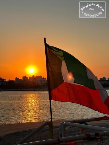 a flag on the beach with the sunset in the background at منتجع اووه يامال البحري في الخيران OOh Yaa Mal in Al Khīrān