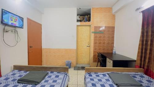 Zimmer mit 2 Betten, einem Schreibtisch und einem TV in der Unterkunft Hotel Image Residential Near Square Hospital in Dhaka