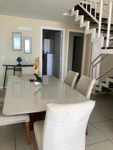 a dining room with a white table and chairs at Apartamento Vista total do Mar uma cobertura a 400m do Beach Park no Porto das Dunas Aquiraz Condomínio Terramaris Piscina ampla Parque infantil Sauna Estacionamento privado in Aquiraz