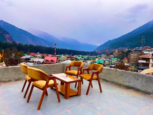 drie stoelen en een tafel op een balkon met uitzicht bij Kawayat INN in Bhavnagar