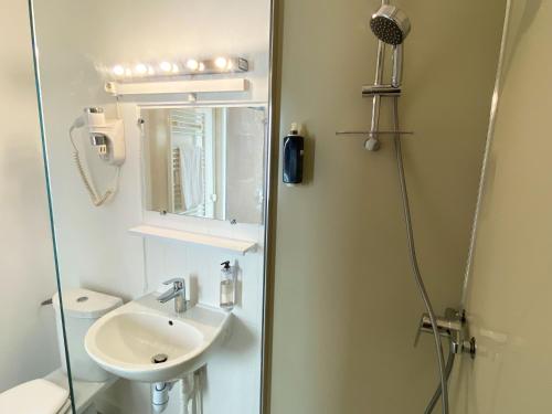 a bathroom with a sink and a shower with a mirror at Maison Esperanza hôtel et appartement in Noirmoutier-en-l'lle