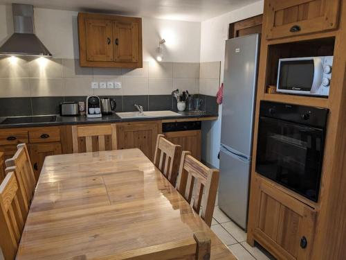 une cuisine avec une table en bois et un réfrigérateur blanc dans l'établissement Spacieux T3 coeur de station, à Bernex