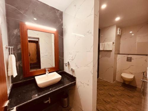 a bathroom with a sink and a toilet and a mirror at Samantha Guest House in Bhavnagar