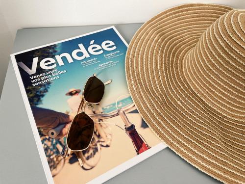 a magazine with a hat and a pair of sunglasses at Maison Esperanza hôtel et appartement in Noirmoutier-en-l'lle