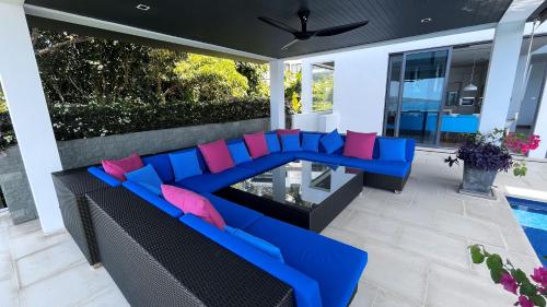 a patio with a blue couch and pink pillows at 07 - Luxurious Haven with Mesmerizing Views in Surin Beach